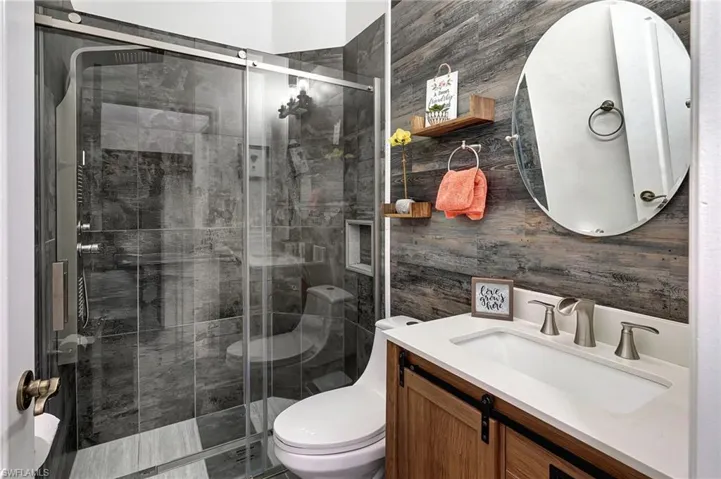 Bathroom featuring toilet, walk in shower, and vanity