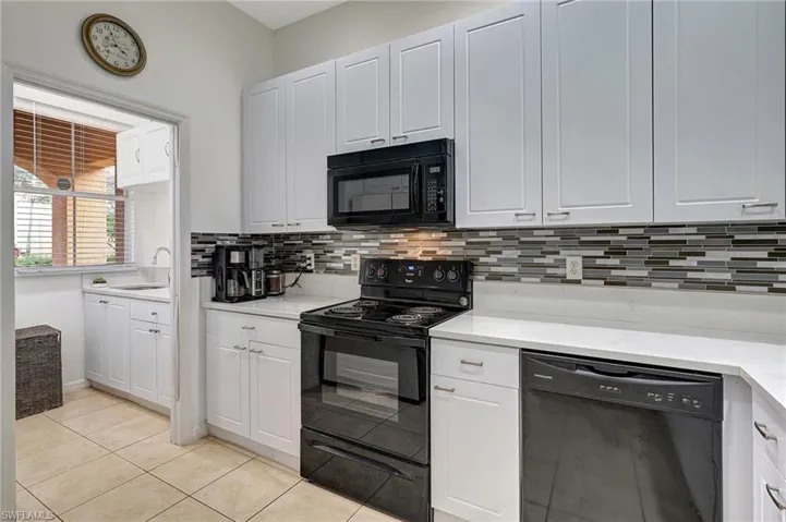 Kitchen featuring black appliances, white cabinetry, sink, and light tile patterned floors