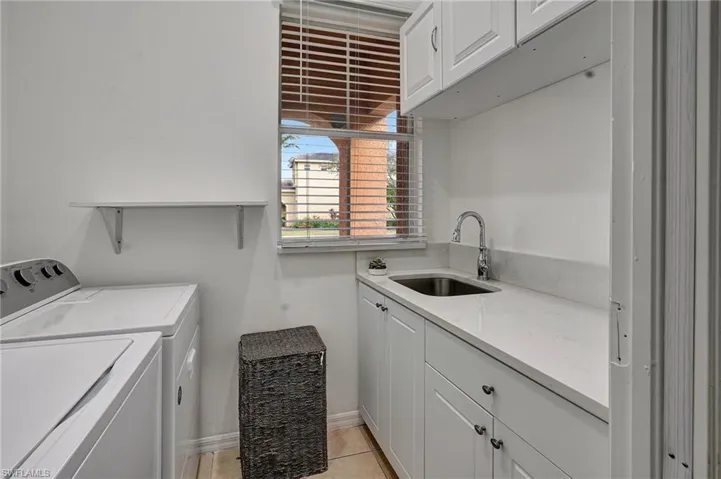 Laundry room featuring sink, cabinets, washer and clothes dryer, and light tile patterned floors
