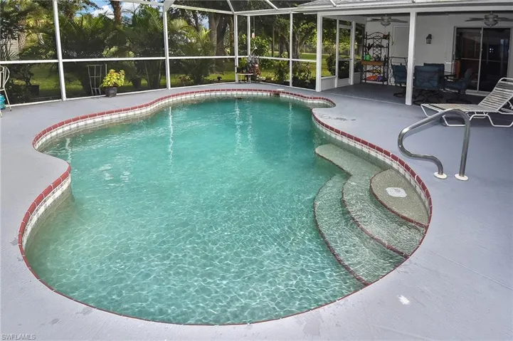 View of swimming pool with glass enclosure, a patio area, and ceiling fan
