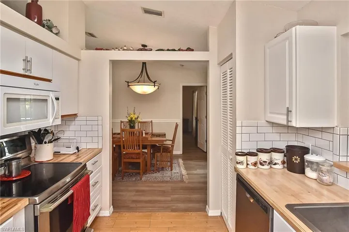Kitchen featuring white cabinetry, decorative backsplash, light wood-type flooring, and stainless steel appliances
