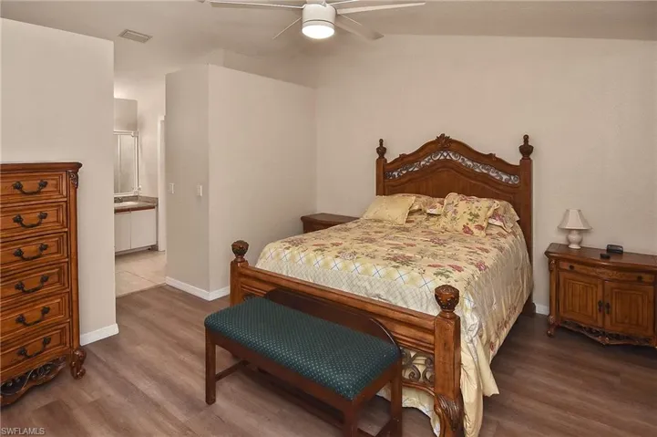 Bedroom with lofted ceiling, ceiling fan, connected bathroom, and hardwood / wood-style floors