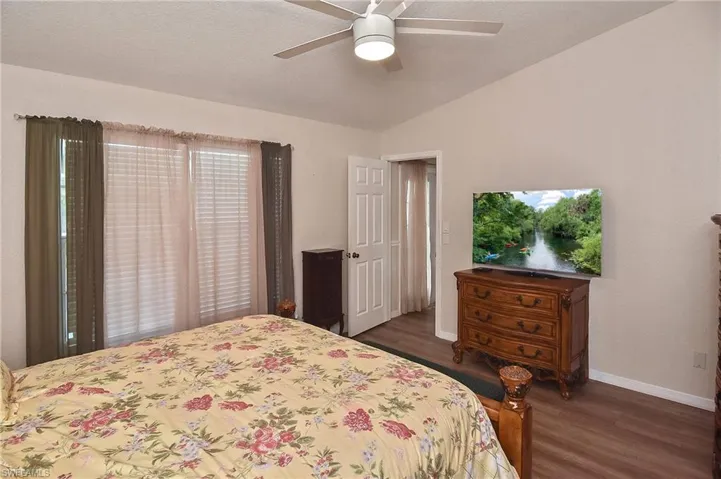 Bedroom with ceiling fan, vaulted ceiling, and dark wood-type flooring