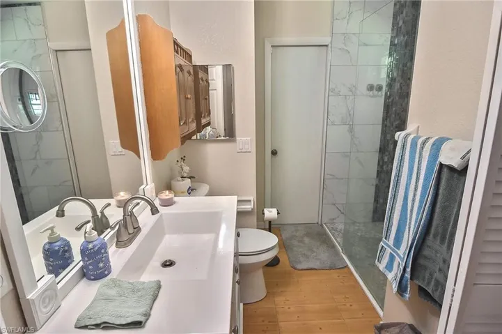 Bathroom featuring vanity, walk in shower, wood-type flooring, and toilet