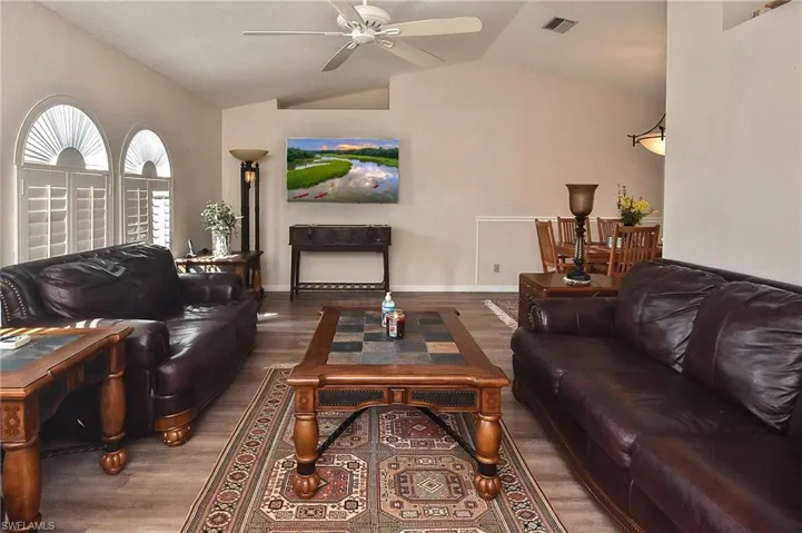 Living room featuring ceiling fan, vaulted ceiling, and dark wood-type flooring