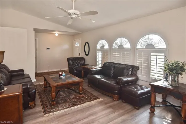Living room featuring lofted ceiling, ceiling fan, and light wood-type flooring