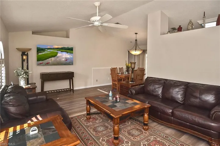 Living room with high vaulted ceiling, ceiling fan, and hardwood / wood-style floors