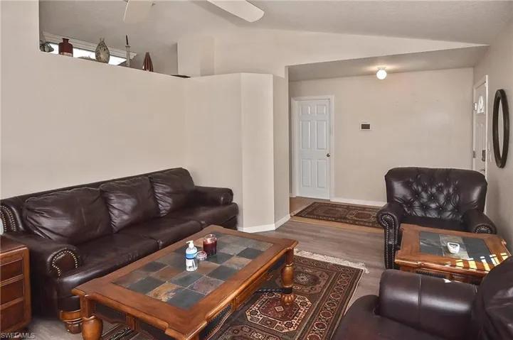 Living room with ceiling fan, hardwood / wood-style flooring, and vaulted ceiling