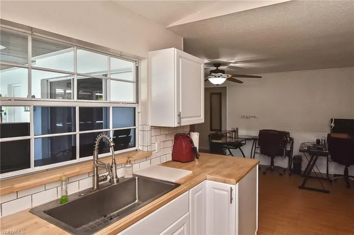 Kitchen with white cabinetry, hardwood / wood-style flooring, tasteful backsplash, ceiling fan, and sink