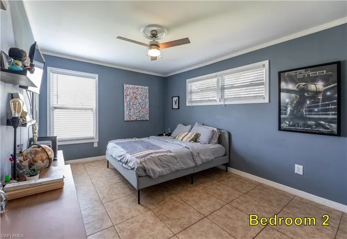 Bedroom featuring crown molding, light tile patterned floors, baseboards, and ceiling fan