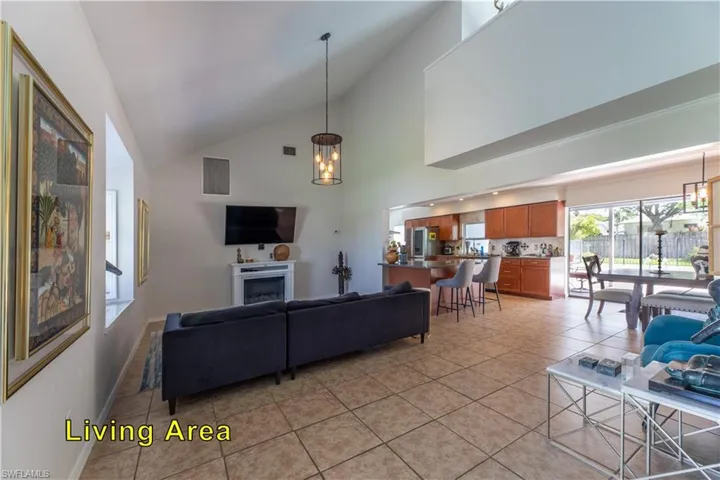 Living area with a notable chandelier, a fireplace, light tile patterned floors, visible vents, and high vaulted ceiling
