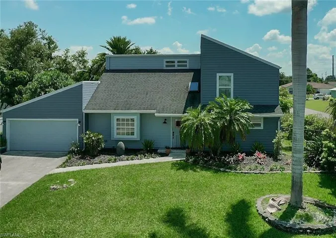 Mid-century modern home with a shingled roof, an attached garage, and a front yard