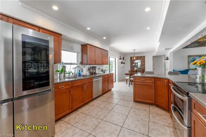 Kitchen with crown molding, brown cabinetry, and appliances with stainless steel finishes
