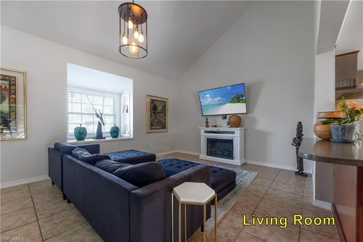 Living area with light tile patterned floors, baseboards, high vaulted ceiling, and a fireplace