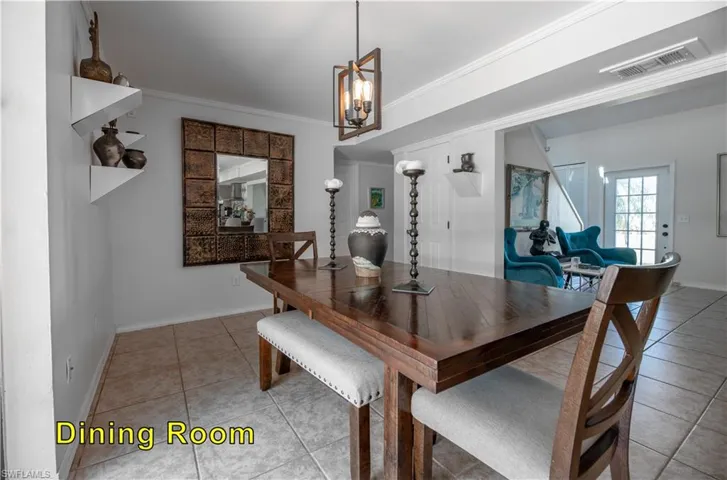 Dining area with a notable chandelier, baseboards, light tile patterned floors, crown molding, and visible vents