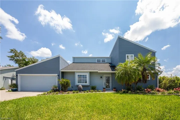 View of front of property featuring concrete driveway, an attached garage, a shingled roof, and a front yard