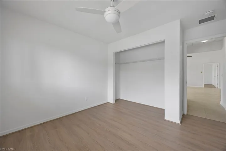 Unfurnished bedroom with wood finished floors, a closet, baseboards, and a ceiling fan