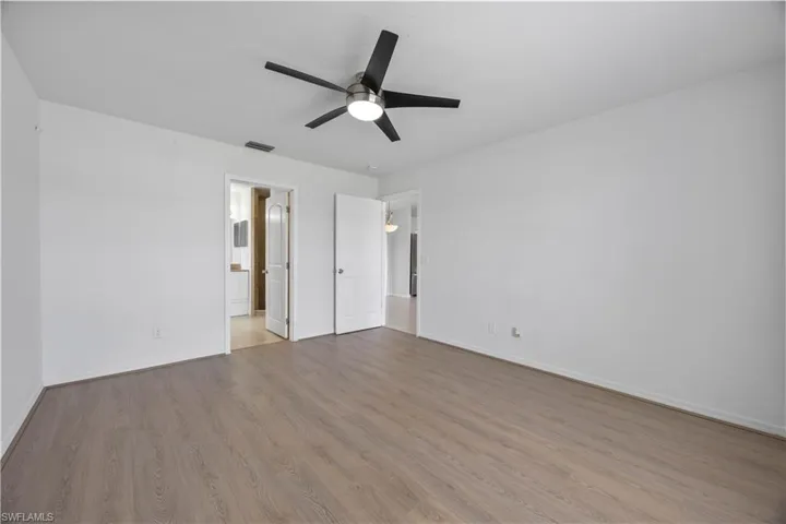 Unfurnished bedroom featuring baseboards, wood finished floors, and ensuite bath