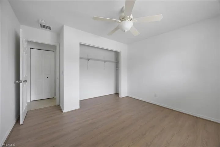Unfurnished bedroom with wood finished floors, baseboards, a closet, and a ceiling fan