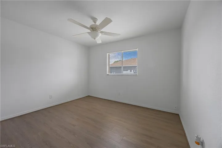 Spare room with wood finished floors, a ceiling fan, and baseboards