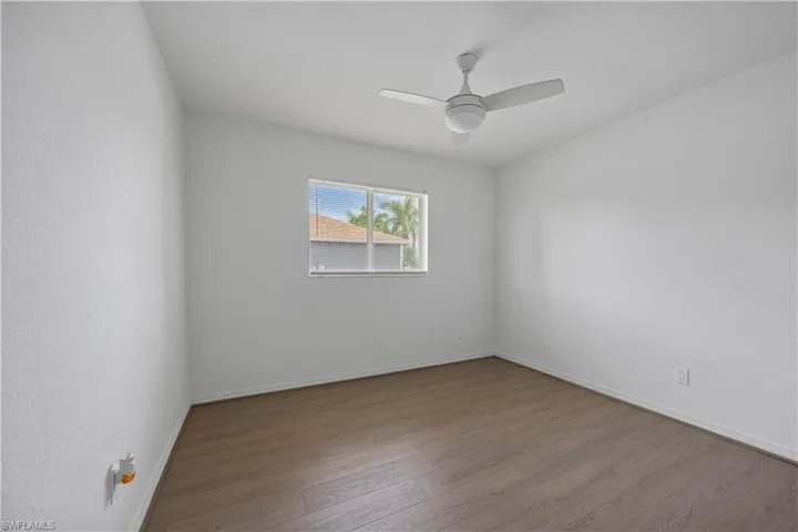 Empty room featuring wood finished floors, ceiling fan, and baseboards
