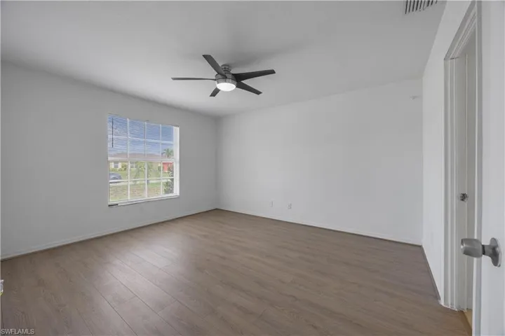 Spare room with ceiling fan, dark wood-style floors, and baseboards