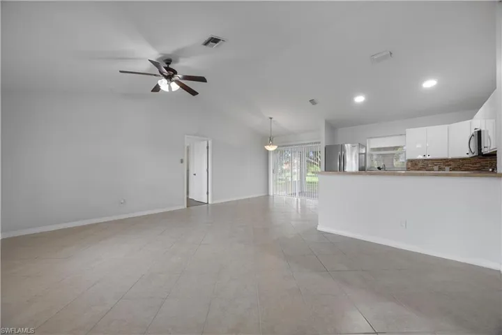 Unfurnished living room with a ceiling fan, vaulted ceiling, baseboards, recessed lighting, and light tile patterned floors