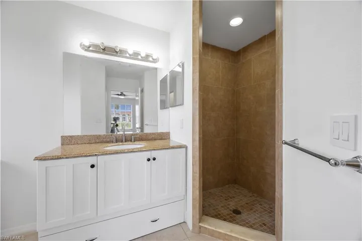 Full bathroom featuring vanity, tiled shower, ceiling fan, and tile patterned flooring