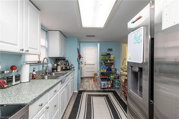 Kitchen with sink, white cabinets, stainless steel fridge, range, and dark wood-type flooring