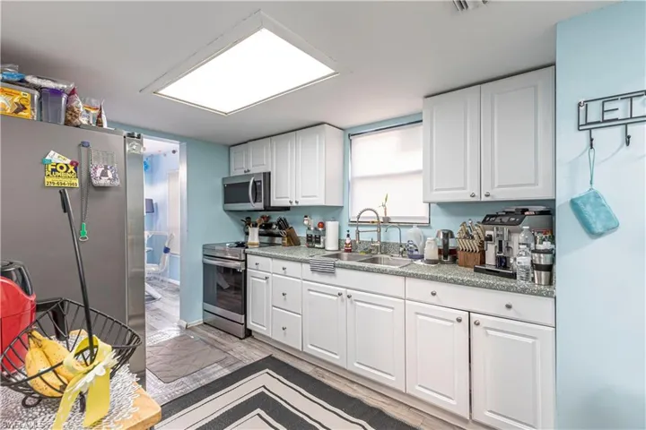 Kitchen featuring stainless steel appliances, white cabinetry, sink, and light hardwood / wood-style flooring
