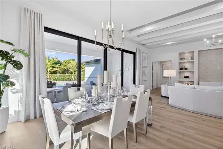 Elegant dining room space features a timeless chandelier, classy dinner place settings. Great views of the outddoor lving space through the wall-wall  sliding glass sliding doors