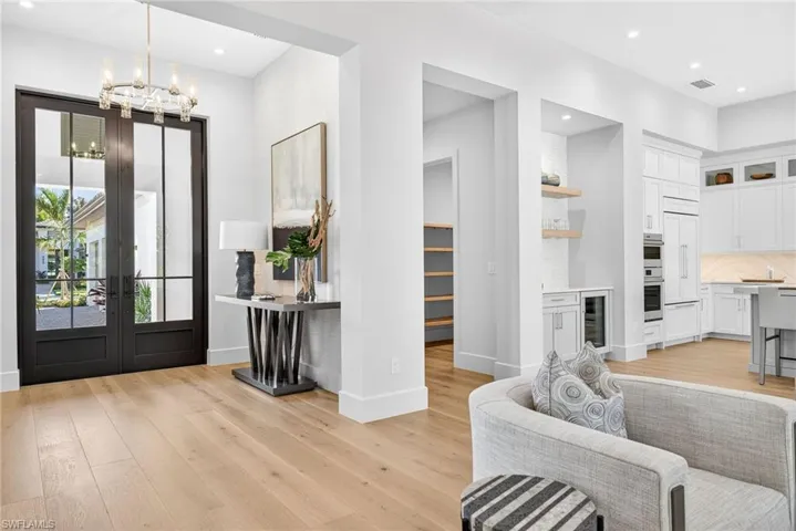 Grand entrance through the 10 ft high double doors, elegant chandelier overhead with a pretty contemporary side table, picture and decor