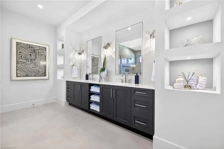 The master suites spacious bathroom features dual vanities, built ins, recessed lighting and clean crisp decor
