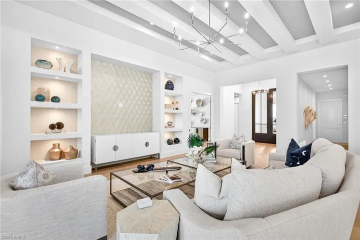 Warm and cozy feel in this living room, pretty chandelier, built in shelves, decorative wall , beam ceiling, all tied in together with the warm wood floors
