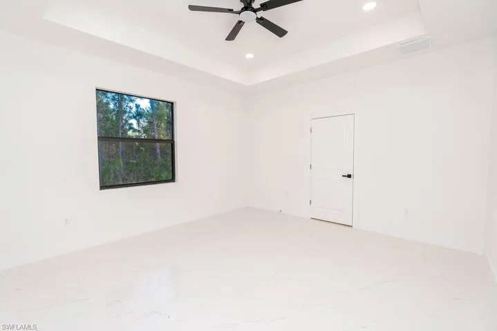 Spare room featuring a tray ceiling, recessed lighting, and a ceiling fan