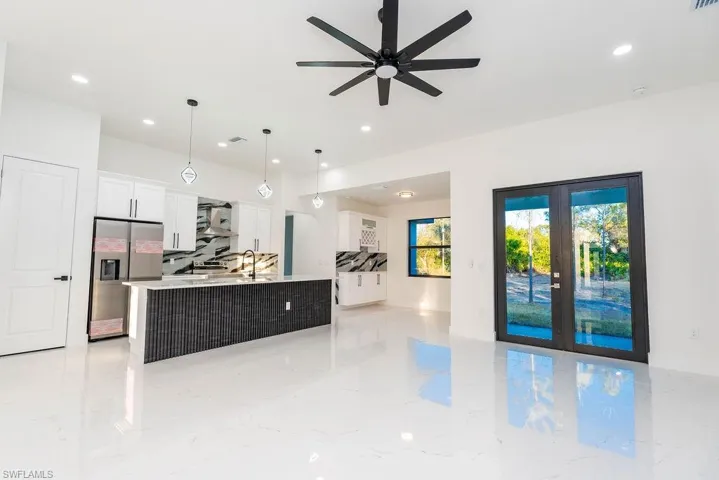 Kitchen featuring french doors, open floor plan, decorative light fixtures, white cabinets, and stainless steel refrigerator with ice dispenser