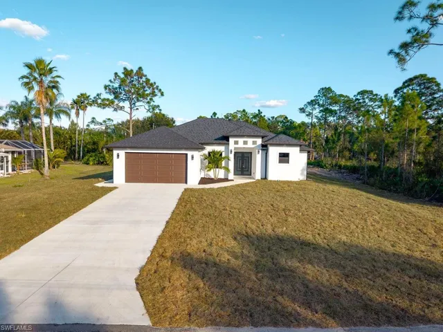 View of front of house featuring a front lawn, concrete driveway, stucco siding, and an attached garage