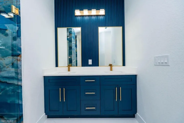 Bathroom with double vanity and a marble finish shower