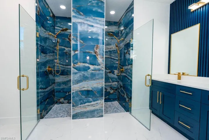Bathroom featuring a marble finish shower, vanity, and light marble finish floors