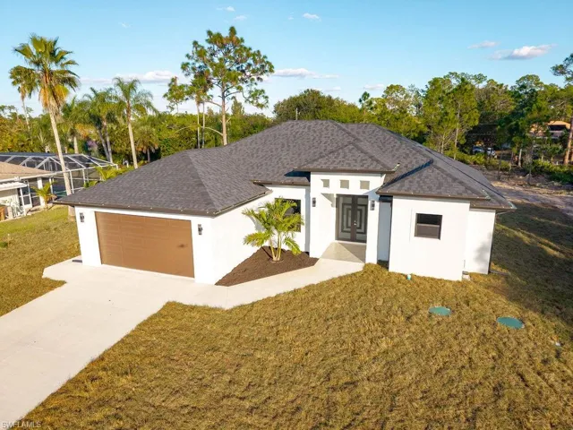View of front facade with stucco siding, a front yard, concrete driveway, and a garage