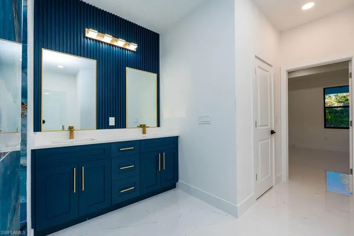 Bathroom featuring double vanity, recessed lighting, and light marble finish floors