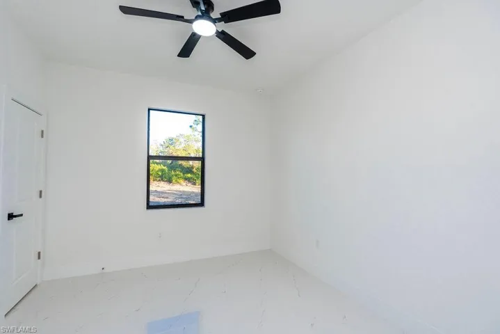 Unfurnished bedroom featuring light marble finish floors and a ceiling fan
