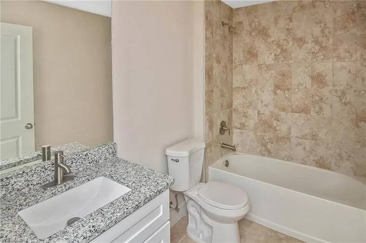 Full bath featuring bathtub / shower combination, vanity, and light tile patterned floors