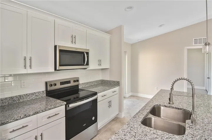 Kitchen with appliances with stainless steel finishes, white cabinetry, light stone counters, pendant lighting, and recessed lighting
