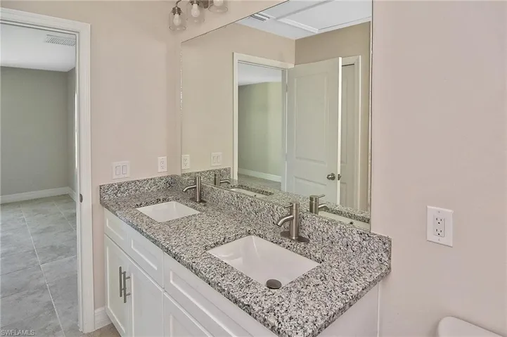 Bathroom with double vanity and light tile patterned floors