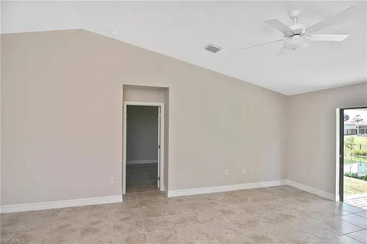 Spare room featuring a ceiling fan, vaulted ceiling, and light tile patterned flooring