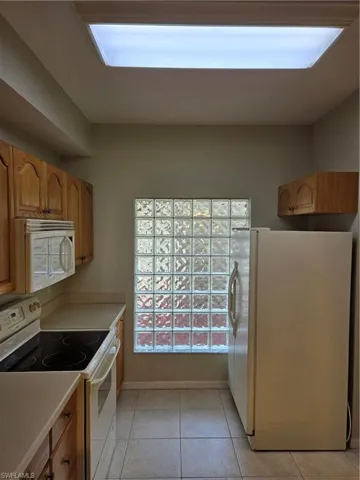 Kitchen featuring refrigerator, light tile patterned floors, and stove