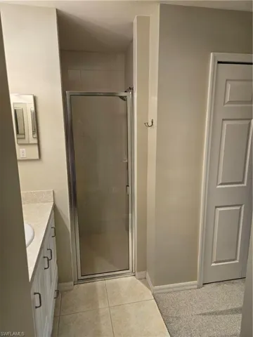 Bathroom featuring tile patterned flooring, a shower with door, and vanity