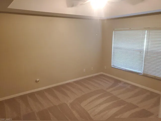 Carpeted spare room featuring ceiling fan
