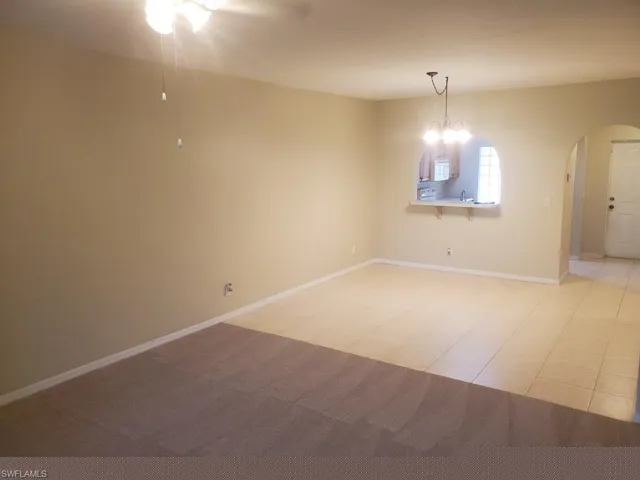 Carpeted empty room featuring sink and ceiling fan with notable chandelier